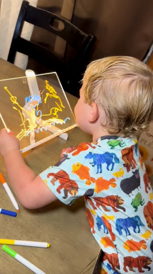 Kleinkind malt leuchtenden Drachen mit LED Zeichenbrett Malvorlage - konzentriert und begeistert