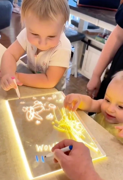 Zwei Kinder malen zusammen am LED Zeichenbrett - gemeinsame kreative Spielzeit am Tisch